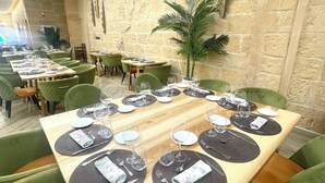 A restaurant with a long wooden table set for a meal, surrounded by green upholstered chairs. - Hotel Castillo Bonavia (Pedrola)