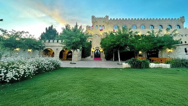 A castle-like building with a red carpet entrance, arched doorways, and flags. - Hotel Castillo Bonavia (Pedrola)