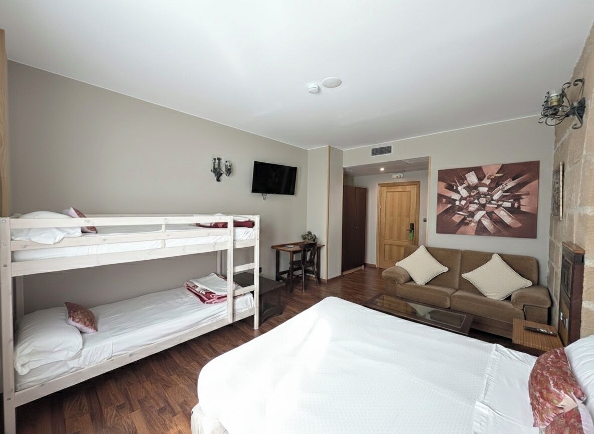 A room with bunk beds, a sofa, a television, and a painting on the wall.
