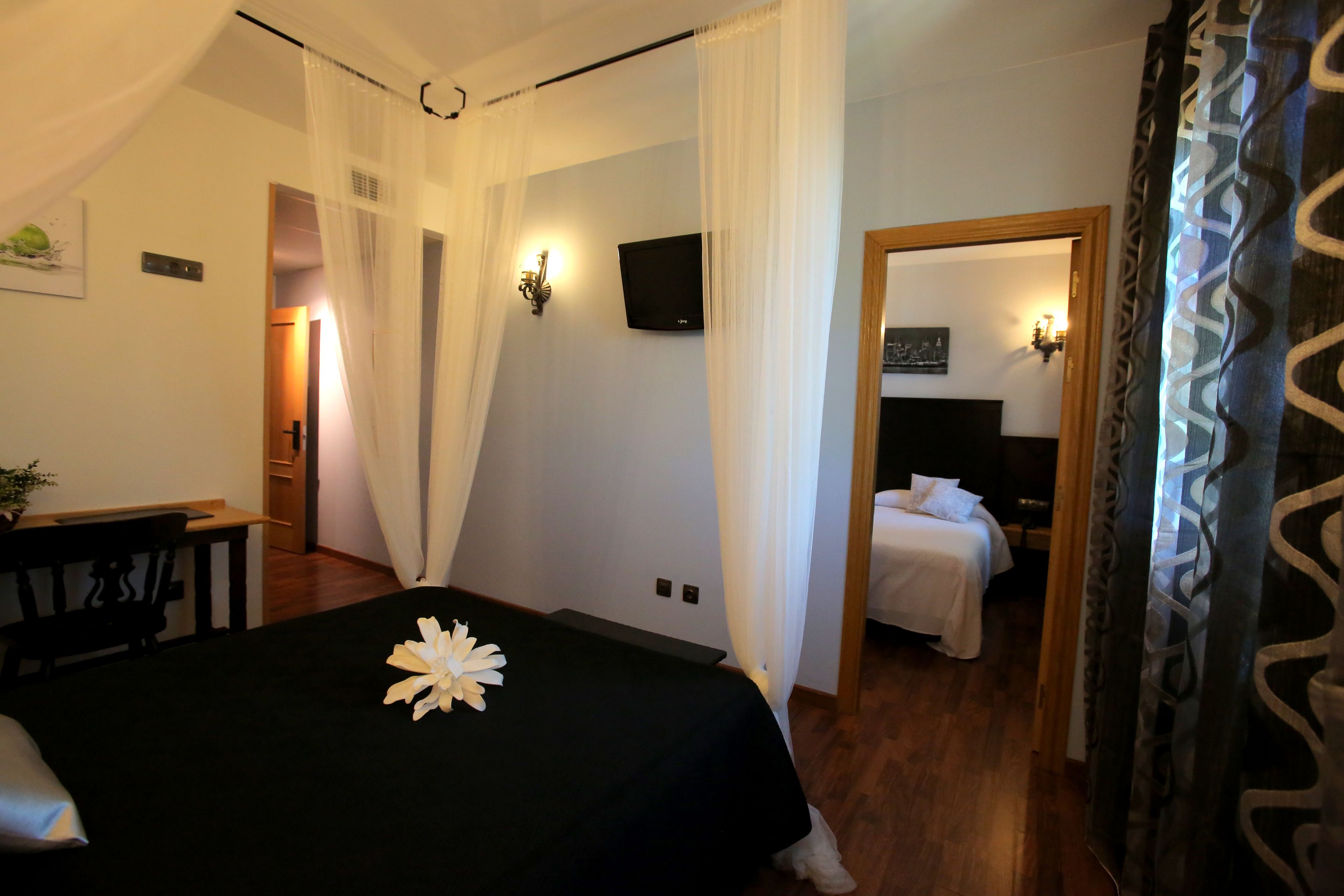 Una habitación de hotel con cama, escritorio y televisión en la pared.