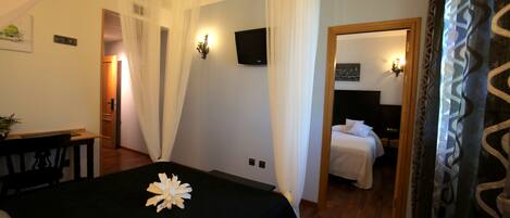 Una habitación de hotel con cama, escritorio y televisión en la pared.