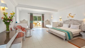 A hotel room with a bed, a desk with a chair, a sofa, a balcony with a view, and a decorative wall piece. - Zodiac Hotel (Hammamet)