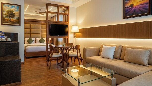 Ein Hotelzimmer mit Bett, Fernseher, Sofa, Esstisch und Couchtisch.