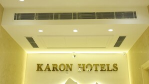 Ein Kronleuchter und das Schild "KARON HOTELS" an der Wand.