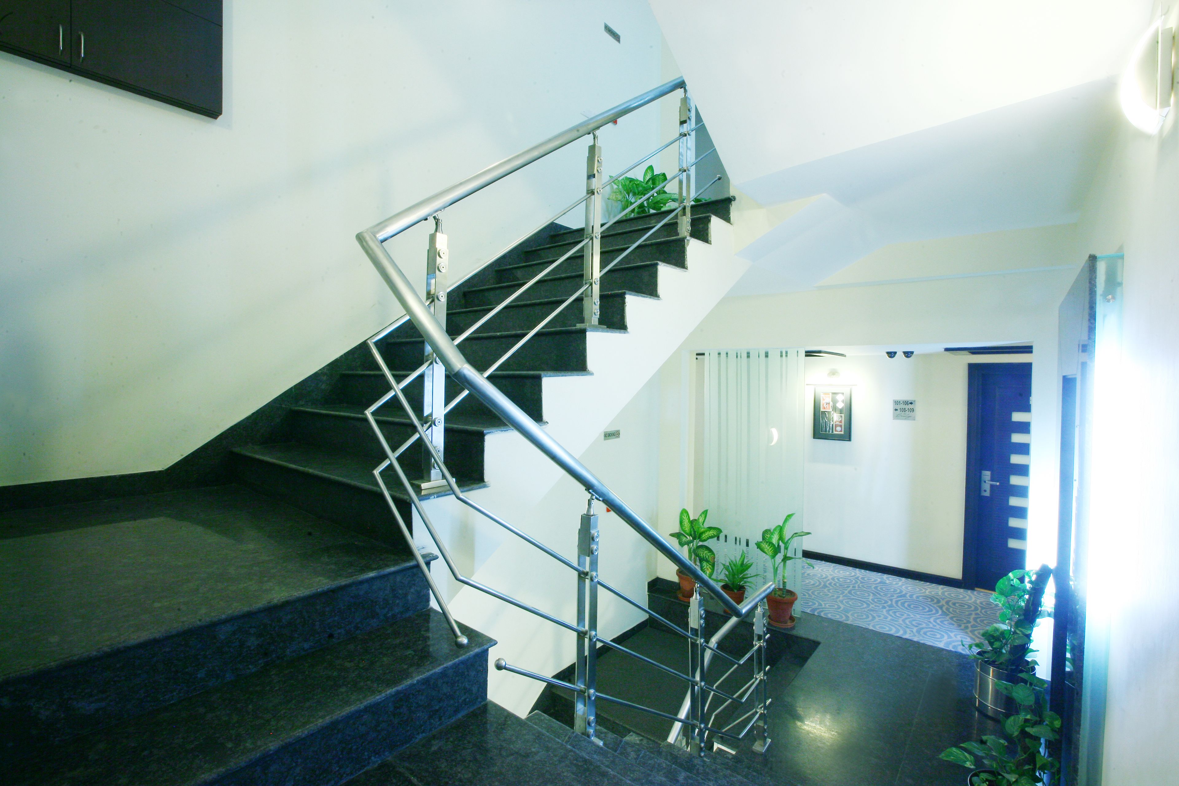Un escalier avec des rampes en métal et des plantes en pot à sa base.