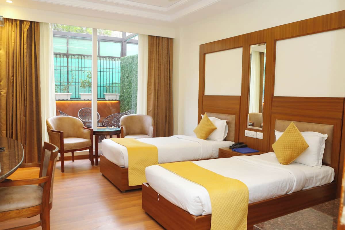 Une chambre d’hôtel avec deux lits, un bureau, des chaises et une grande fenêtre avec des rideaux.