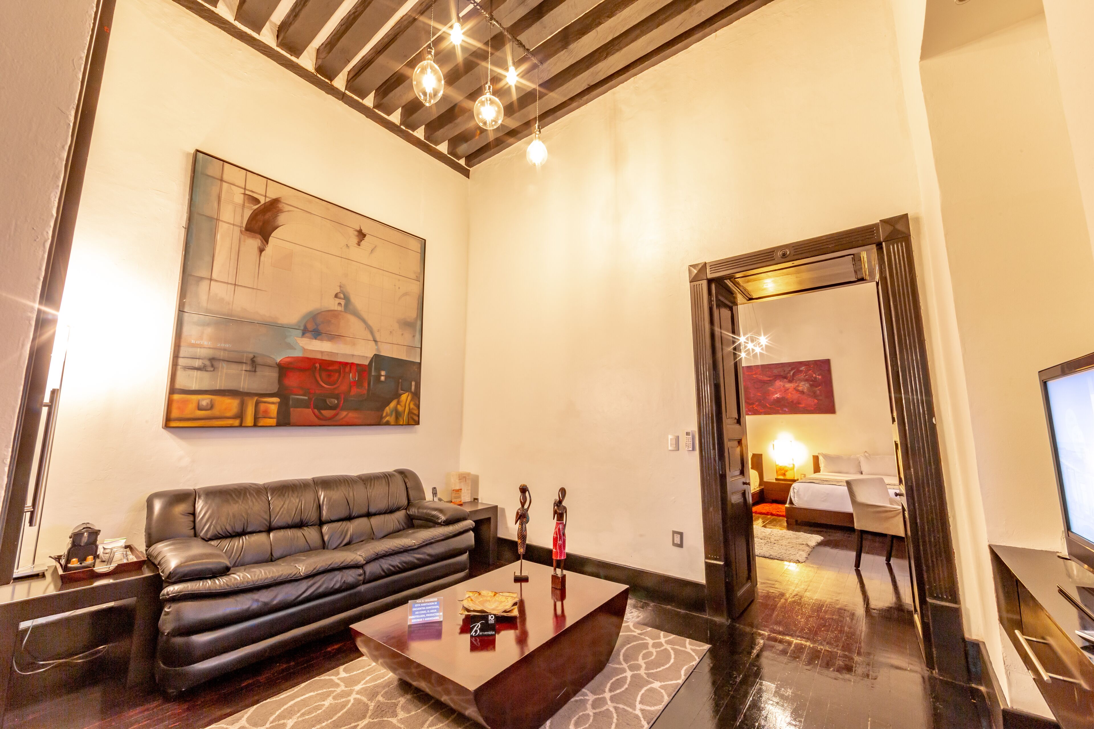 A modern living room with a leather sofa, a coffee table, and a large abstract painting on the wall.