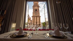 Mesa para dos con vista a una torre histórica a través de una ventana.