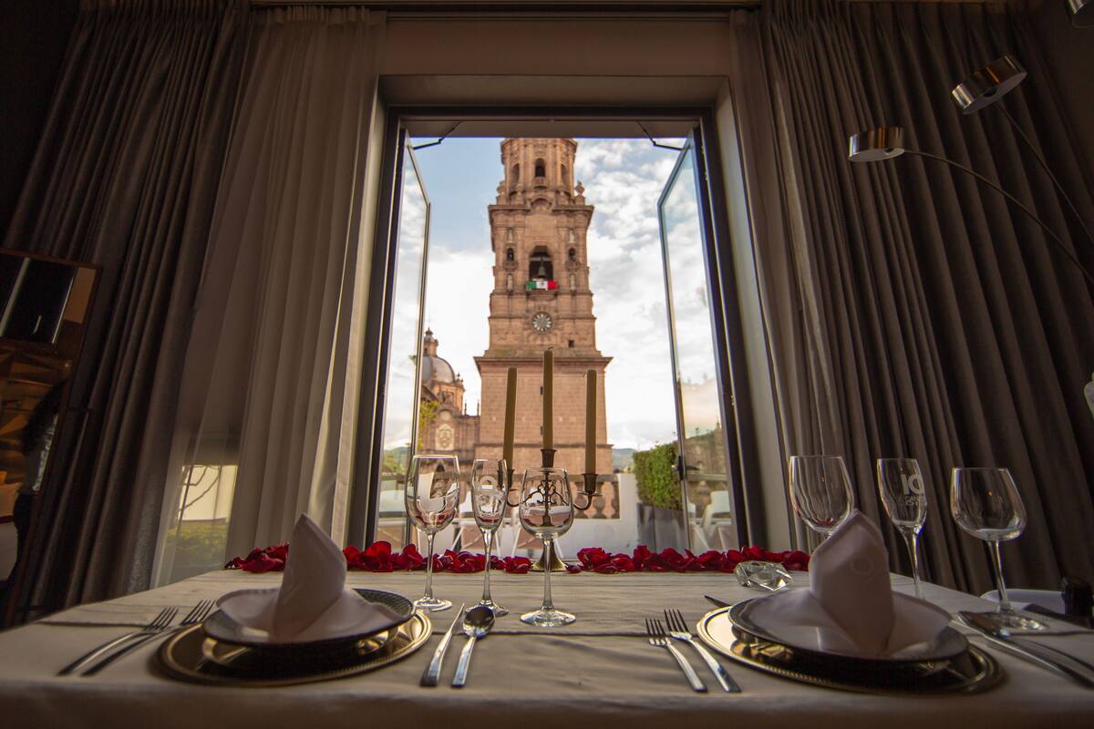 Mesa para dos con vista a una torre histórica a través de una ventana.