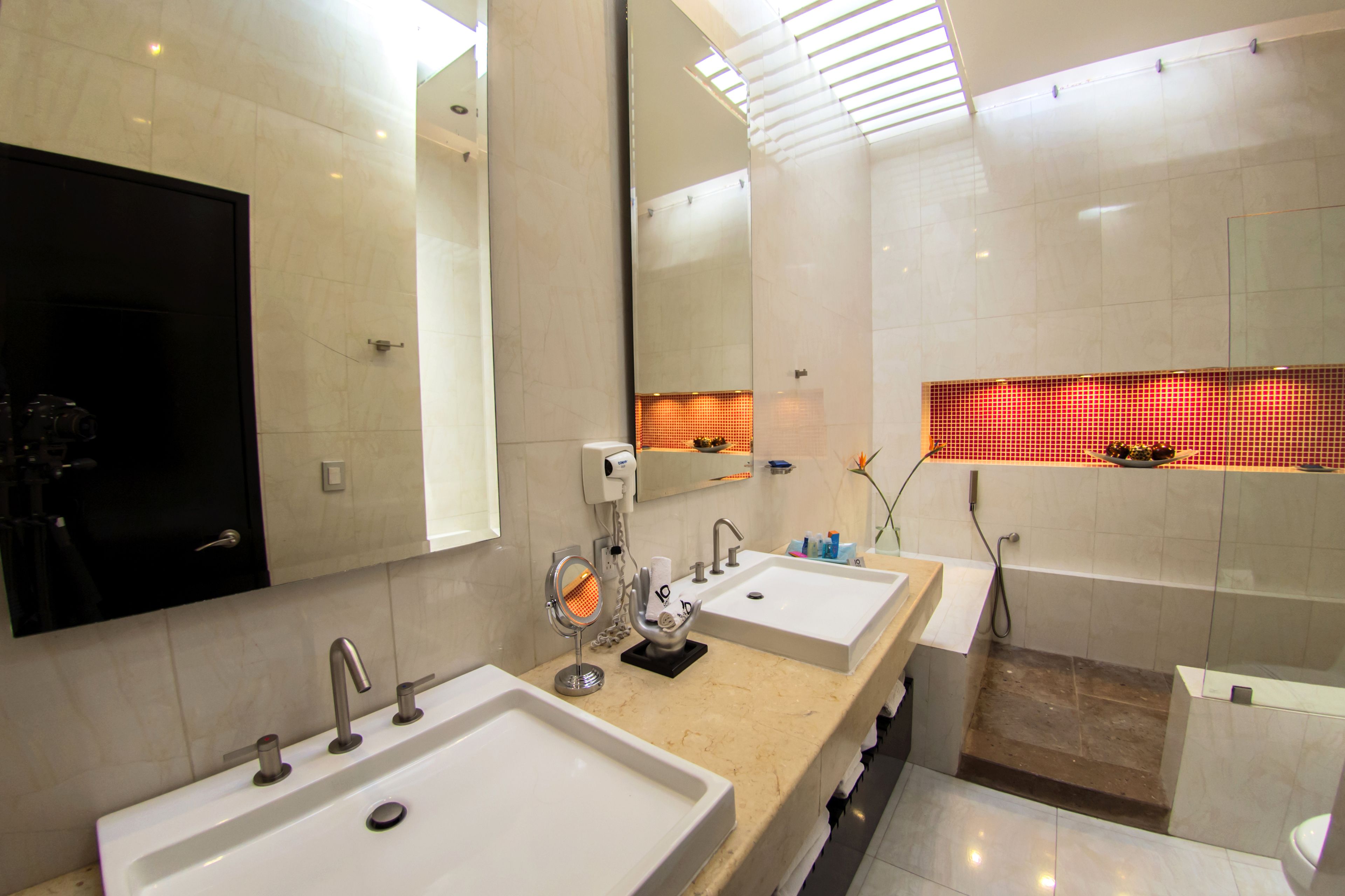 Une salle de bain moderne avec deux lavabos, un miroir et un espace douche.