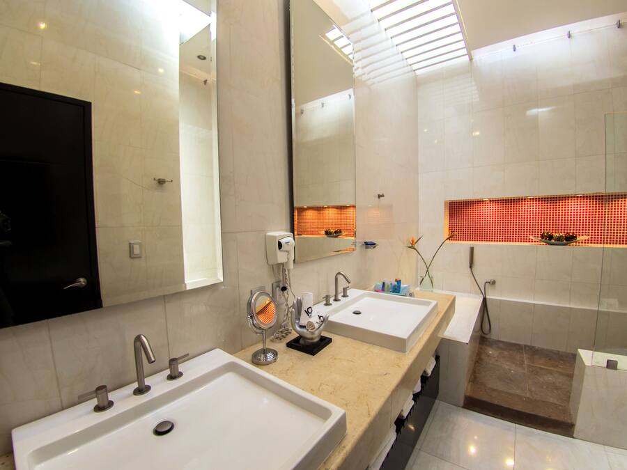 Une salle de bain moderne avec deux lavabos, un miroir et un espace douche.