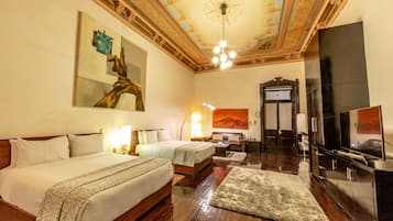 A hotel room with two beds, a large painting, a television, and a fireplace.