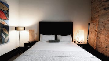 Hotellihuone, jossa on suuri sänky, pääty, kaksi yöpöytää ja seinä, jossa on koristeellinen kivipinta.
