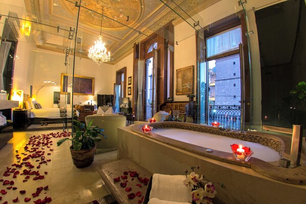 Een luxueuze spa-ruimte met een groot bad, rozenblaadjes op de vloer en een kroonluchter.