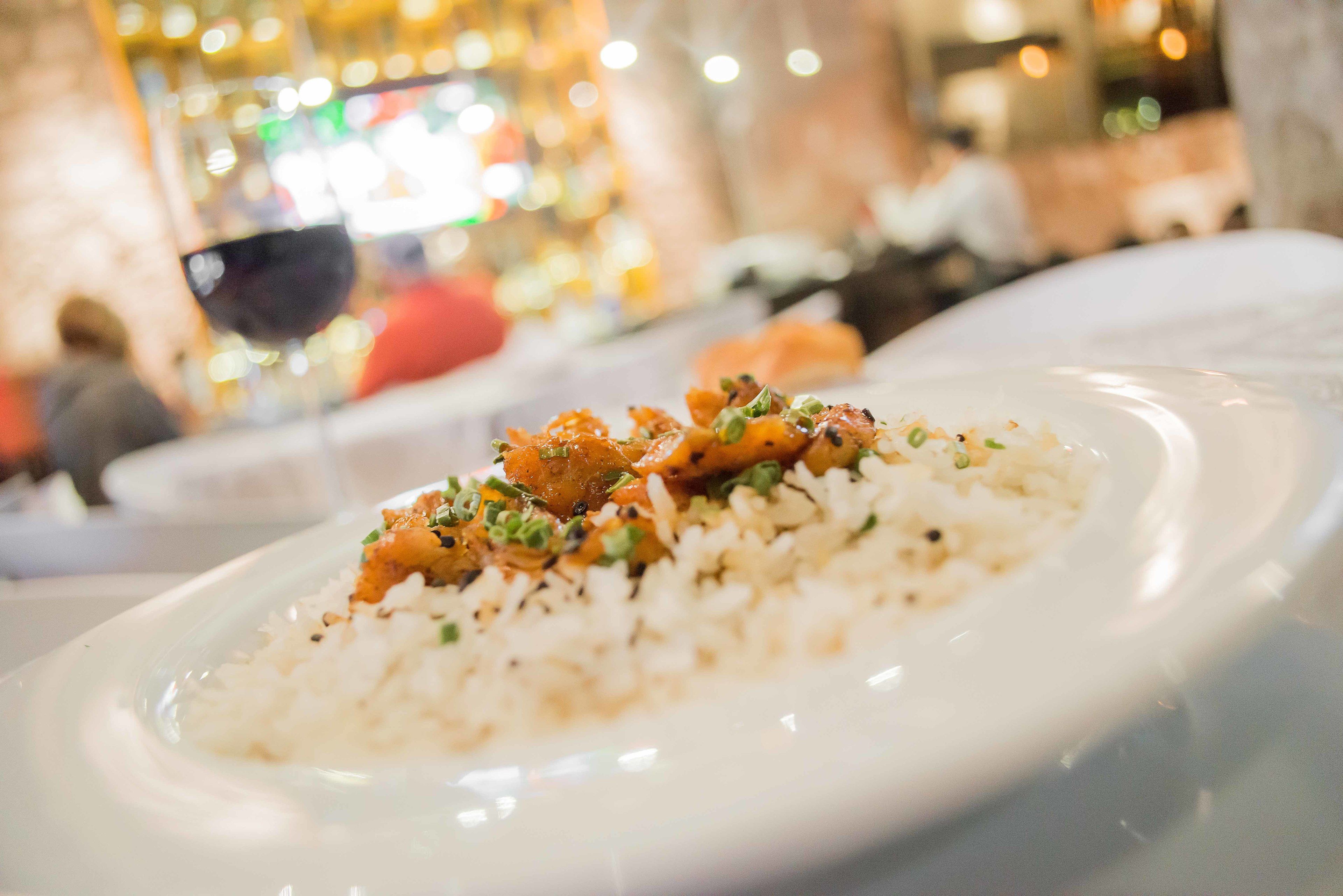 Plato de arroz blanco con un guiso de carne encima, decorado con hierbas verdes, servido en un plato blanco.