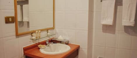 Un baño con tocador de madera, un lavabo, un espejo, un perchero para toallas y un inodoro.