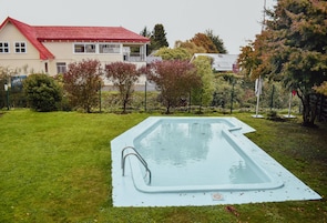 Una piscina al aire libre de temporada, sombrillas