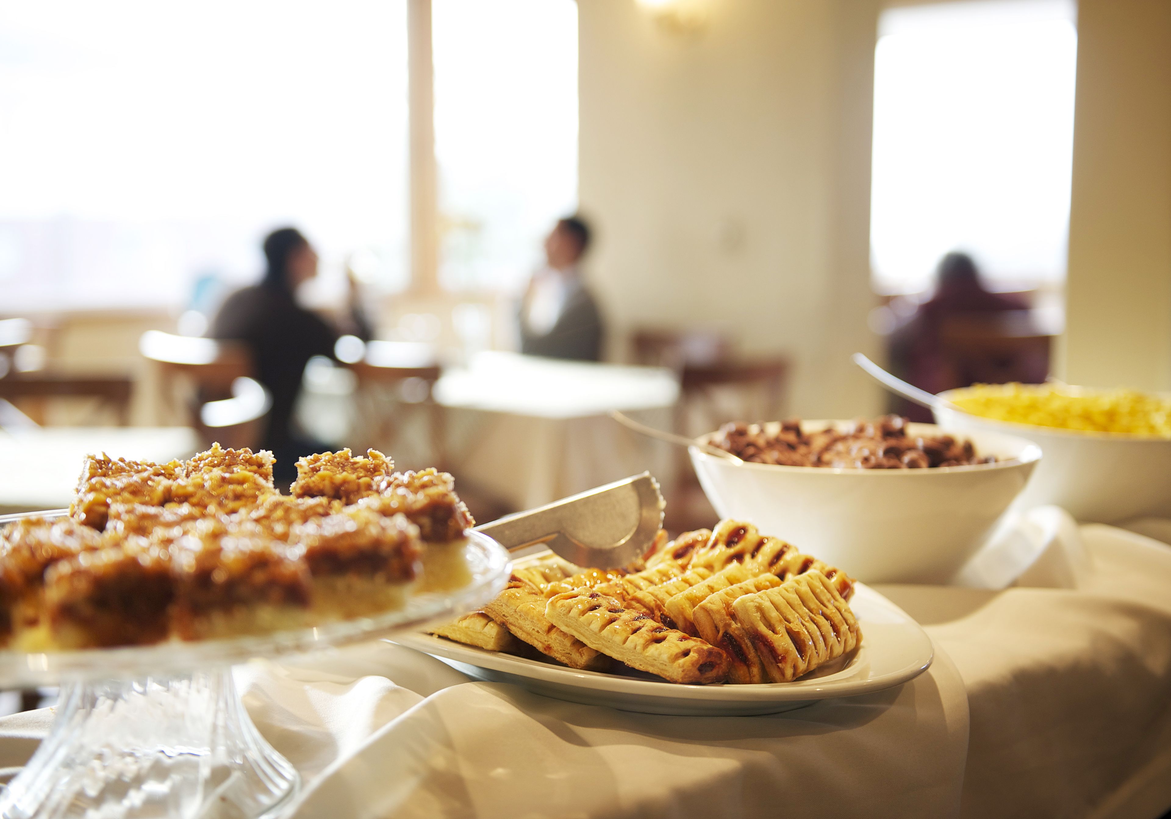 A buffet table with various dishes, including a pie and a bowl of yellow food, in a well-lit dining area.