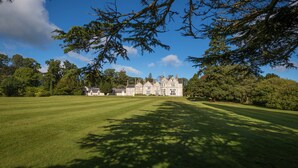 A large, historic building with a well-maintained lawn in front. - Lough Rynn Castle (Mohill)