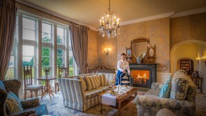 A cozy living room with a fireplace, a chandelier, and a view of the outdoors. - Lough Rynn Castle (Mohill)