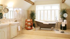 A bathroom with a freestanding bathtub, a large window, and a vanity with a mirror.