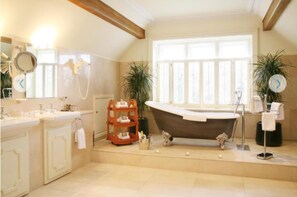 A bathroom with a freestanding bathtub, a large window, and a vanity with a mirror.