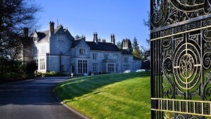 A large stone building with a symmetrical facade, a gated entrance, and a well-maintained lawn. - Lough Rynn Castle (Mohill)