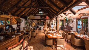 Un restaurant acollidor amb bigues de fusta, mobles de vimet i un paviment de rajola.
