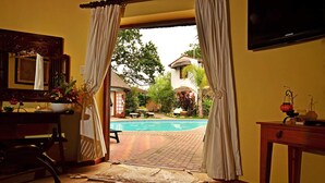 Una porta oberta que dona a una zona de piscina amb vistes a una casa i un jardí.