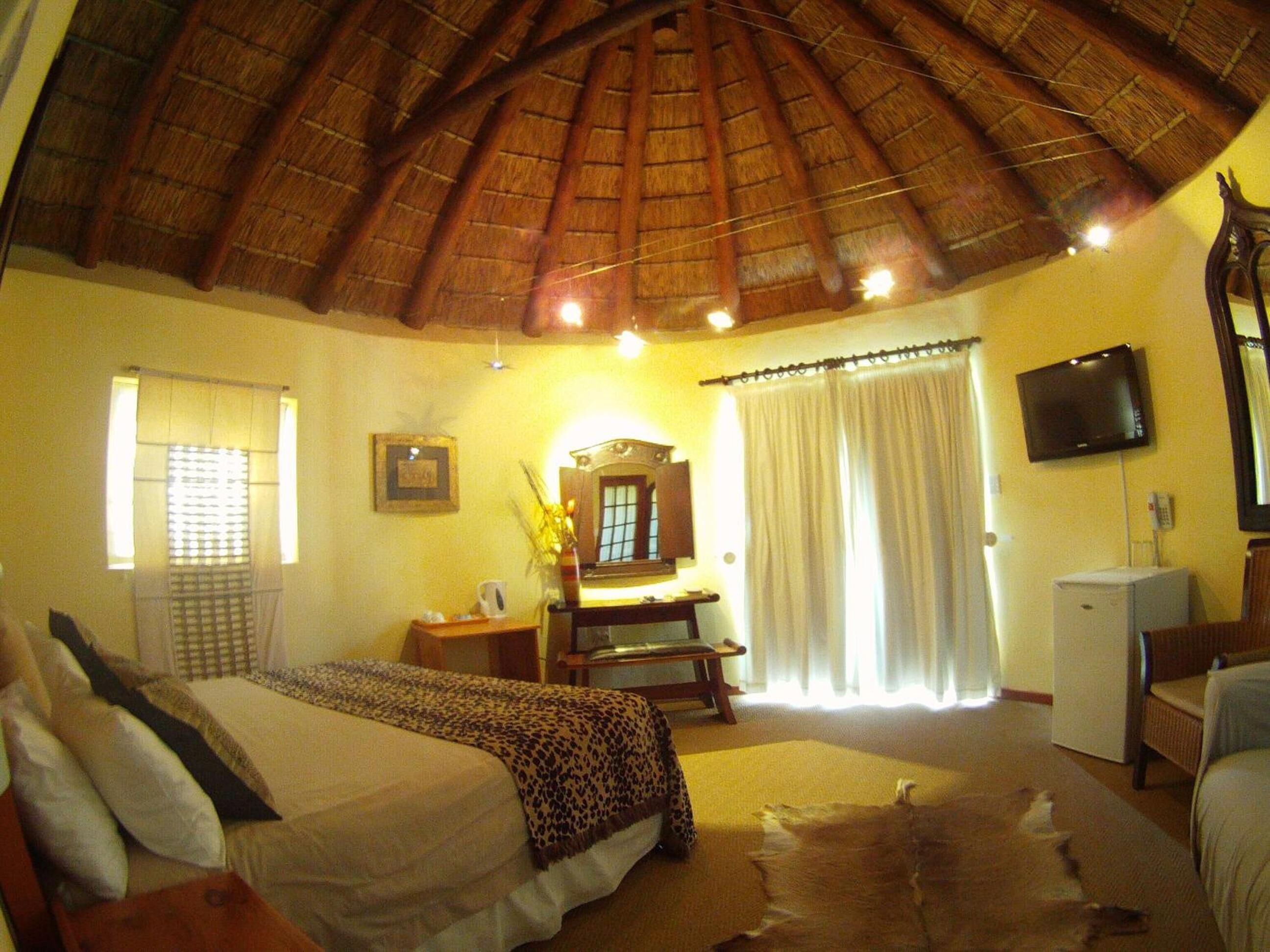 A room with a bed, a desk, a television, and a ceiling fan.