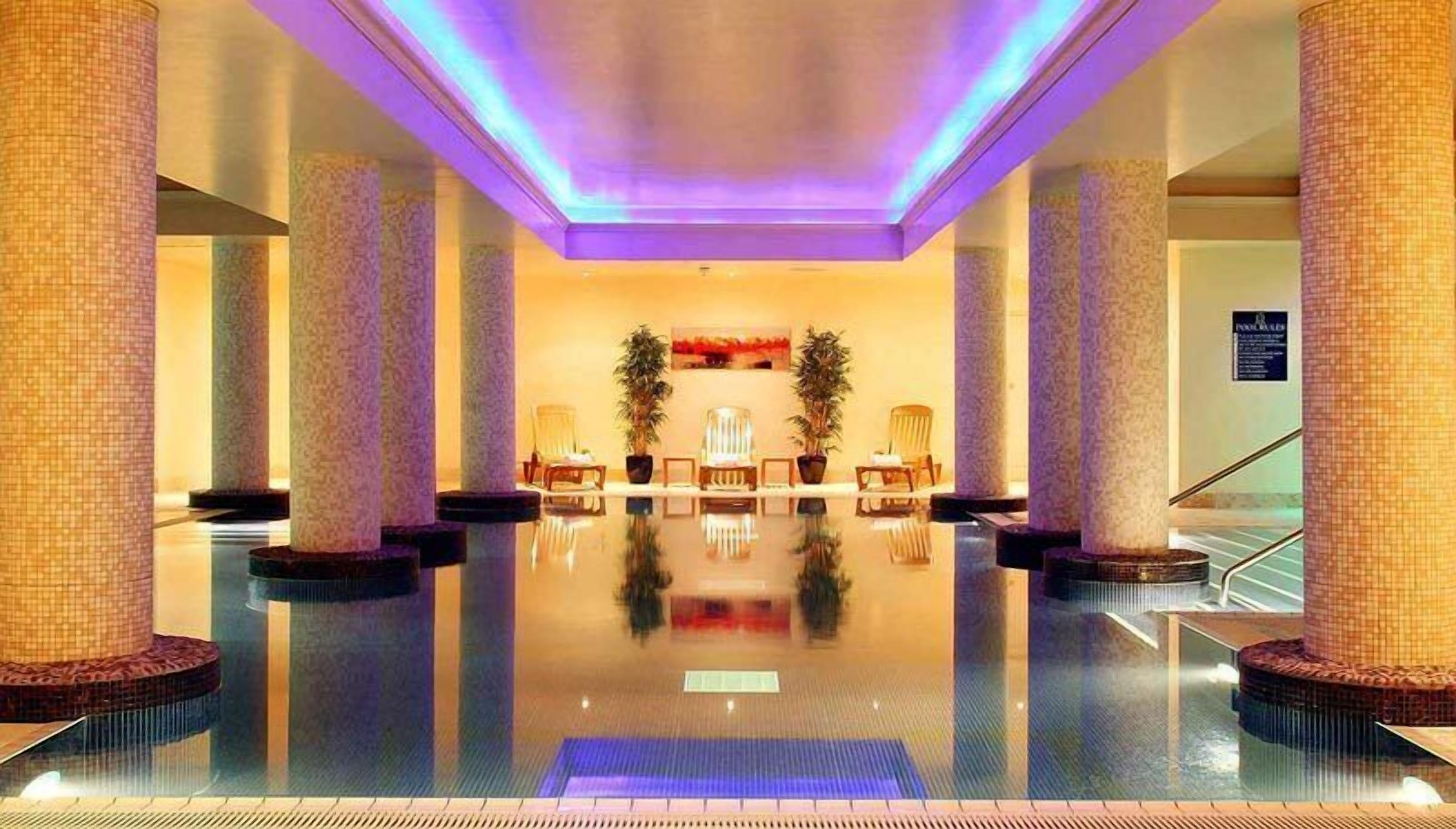 A spacious lobby with a reflective floor, large columns, and seating areas.
