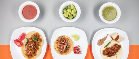 Tre piatti di tacos con guarnizioni diverse e tre piccole ciotole di contorni.