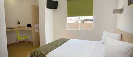 A hotel room with a bed, a desk, a chair, a TV, and a window with a view.