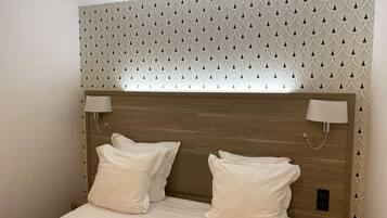 Un letto rifatto con due cuscini e una testiera in legno, con una carta da parati decorata sopra.