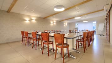 A spacious conference room with a long table and multiple chairs, equipped with water dispensers and a whiteboard.