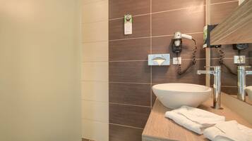 A modern bathroom with a large white sink, a mirror, and a hairdryer mounted on the wall.