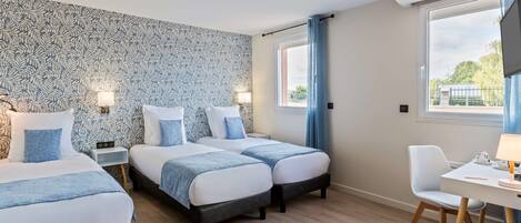 Une chambre d’hôtel avec deux lits, un bureau et une chaise.