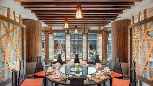 Un comedor de estilo tradicional con mesas redondas, sillas de madera y una mesa de vidrio central.