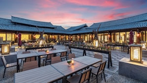 A traditional-style restaurant with wooden tables and chairs, outdoor seating, and lanterns. - InterContinental Lijiang Ancient Town Resort by IHG (Lijiang)