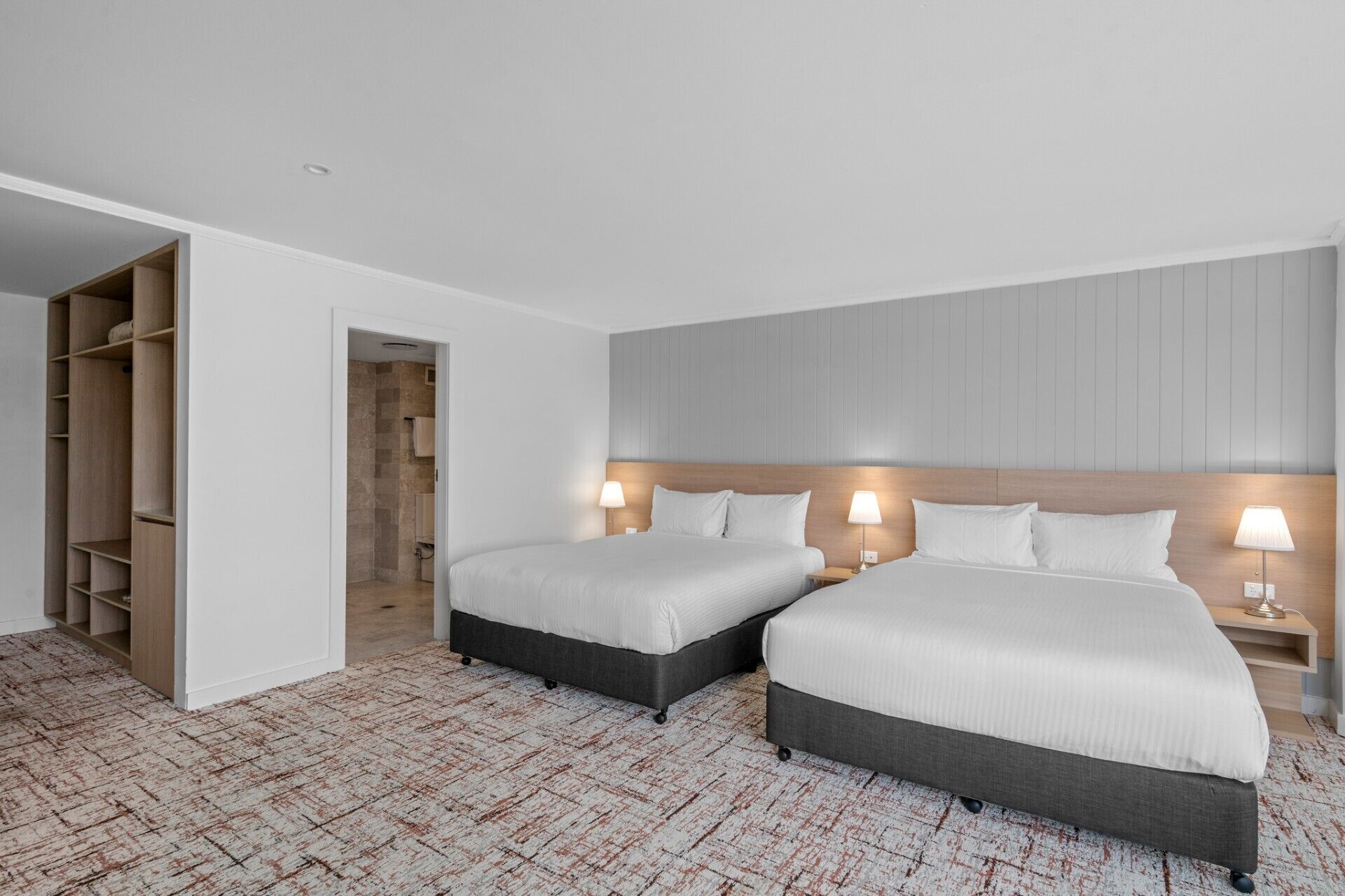 A hotel room with two beds, a walk-in closet, and a bathroom with a shower.