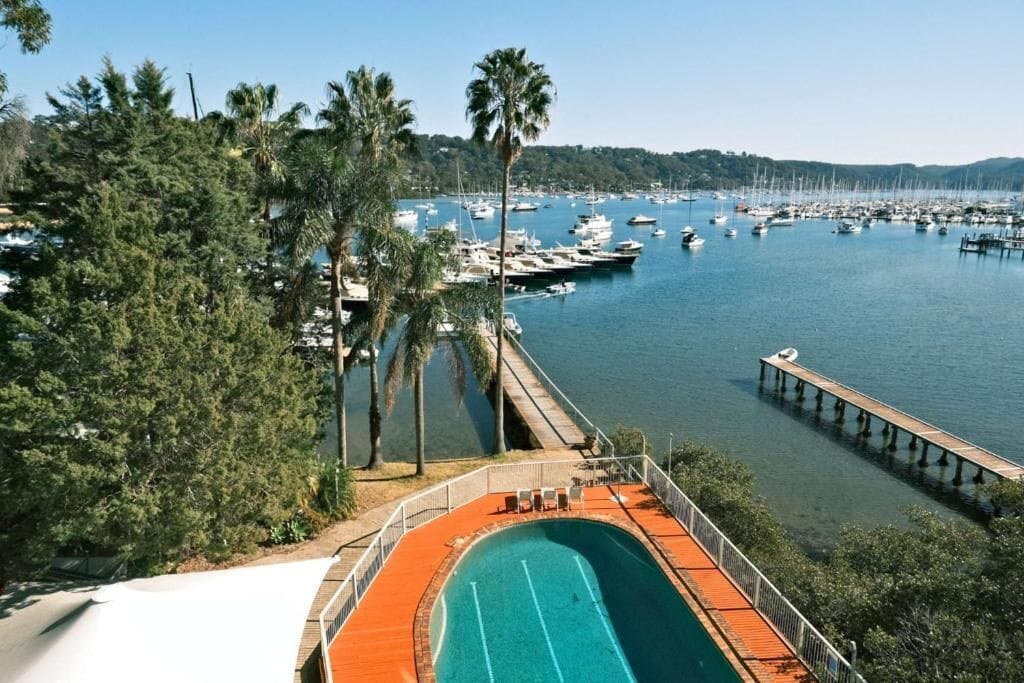 A marina with boats docked, a swimming pool, and a wooden pier.