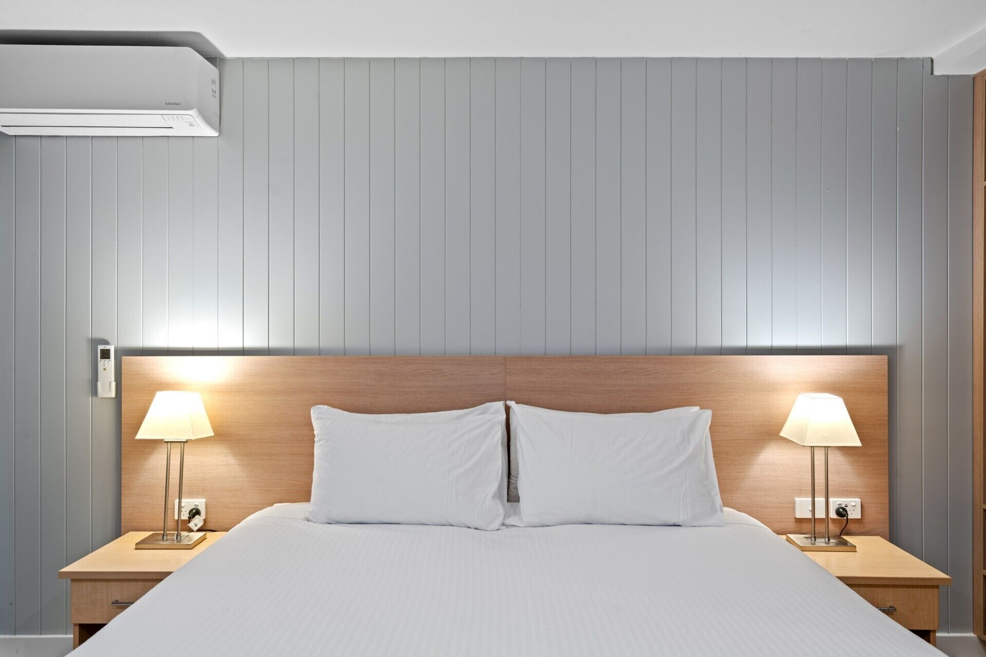 A hotel room with a large bed, two bedside tables with lamps, and a wooden headboard.