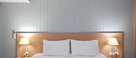 Una habitación de hotel con una cama grande, dos mesitas de noche con lámparas y un cabecero de madera.