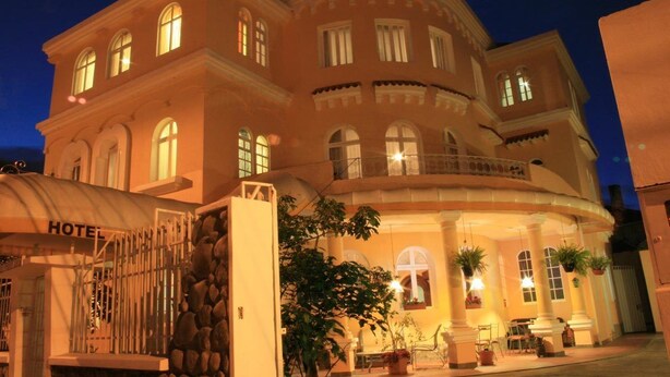A hotel with a curved facade, multiple balconies, and a gated entrance. - Hotel La Casona (Cuenca)