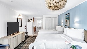 Une chambre d’hôtel avec un grand lit, une télévision, un bureau et un lustre en osier.