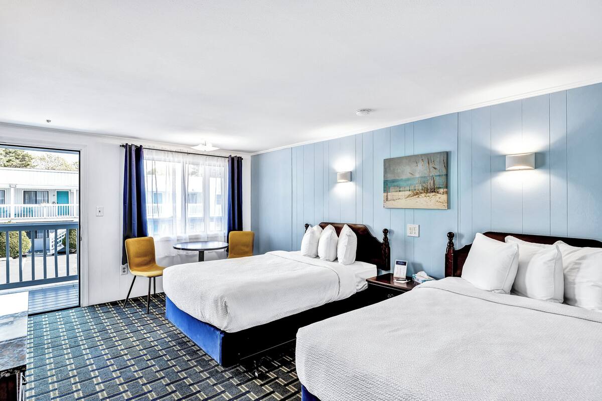 Une chambre d’hôtel avec deux lits, une petite table, une chaise et un balcon avec vue.