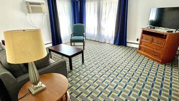 Habitación de hotel con alfombra estampada, televisión, escritorio, silla, lámpara y cómoda.