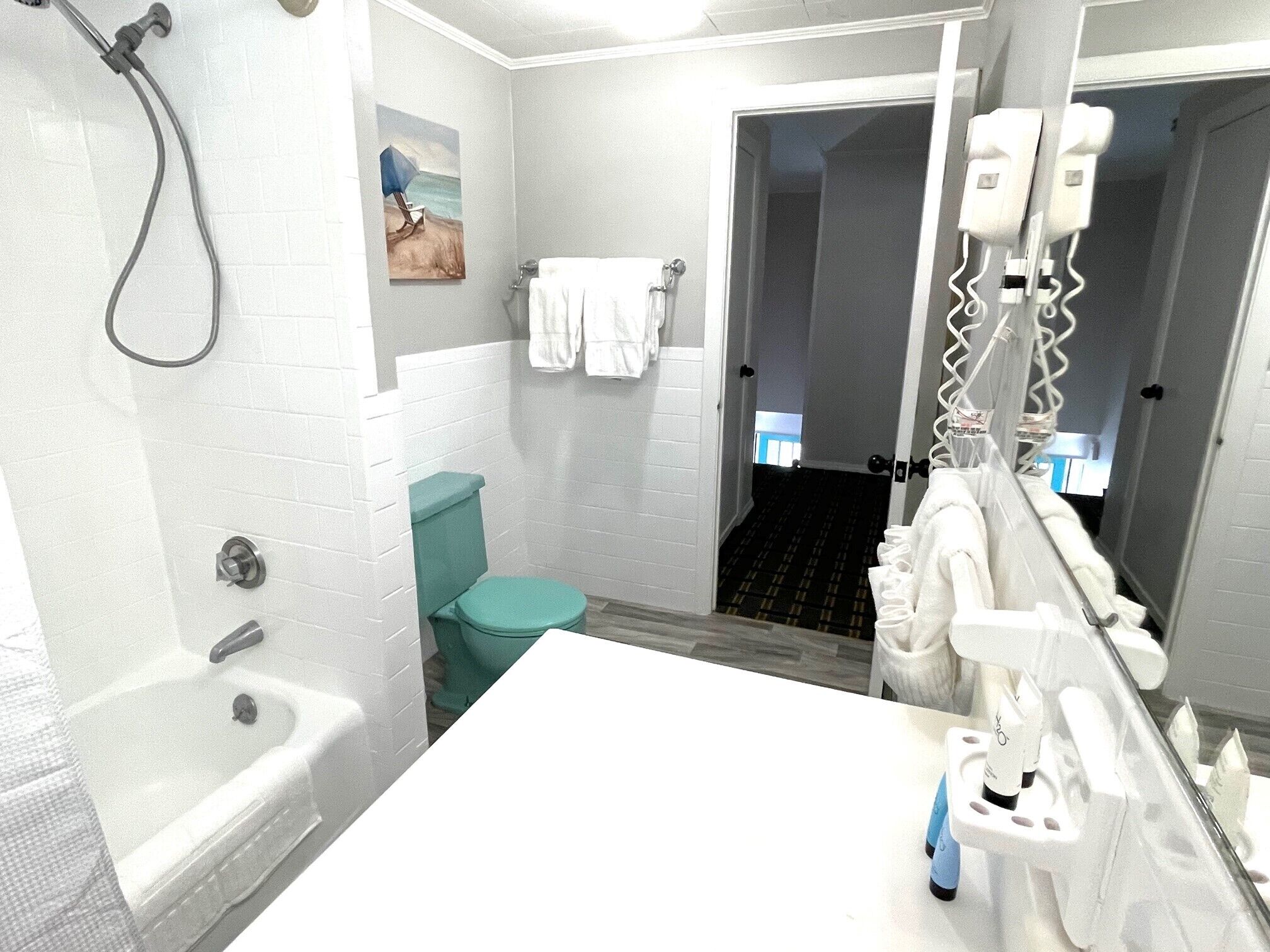 A bathroom with a bathtub, toilet, and shower. There is a towel rack and a mirror.