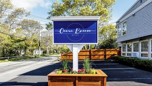Une enseigne de motel portant le nom « Ocean Breeze » et un bac à fleurs rempli de plantes devant l’entrée.