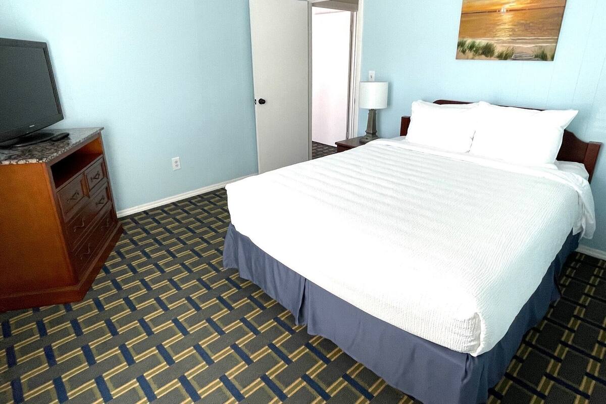 Une chambre d’hôtel avec un lit, un téléviseur posé sur une commode et un tableau accroché au mur.